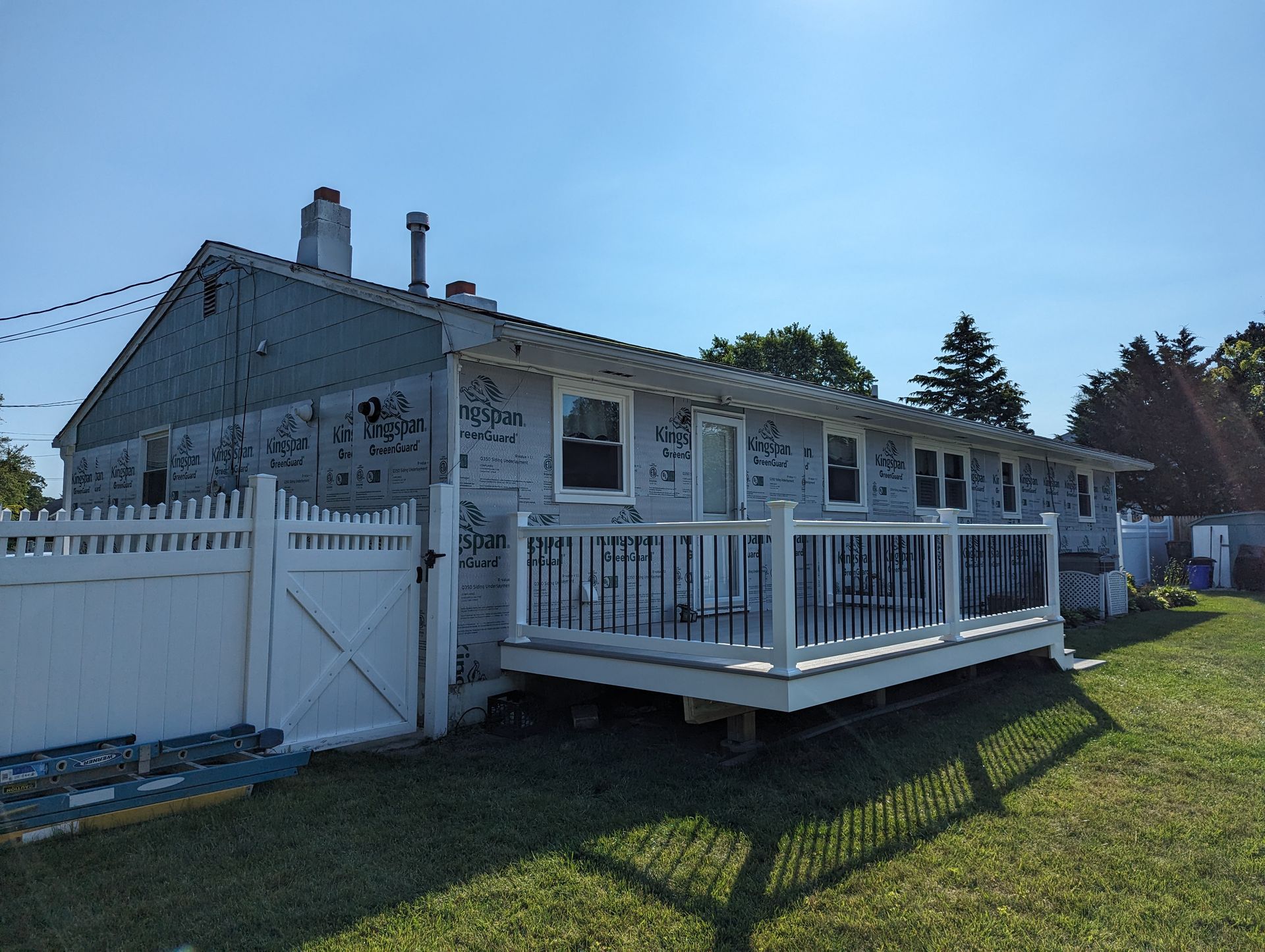 A white house with a white fence and a white deck