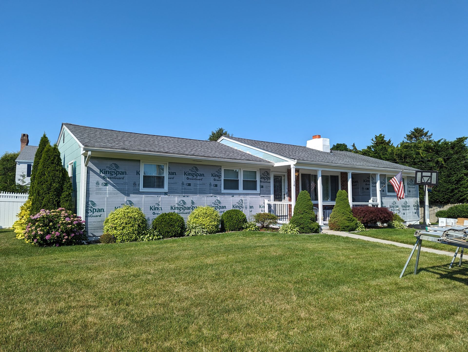 A house with a gray roof is sitting on top of a lush green lawn.