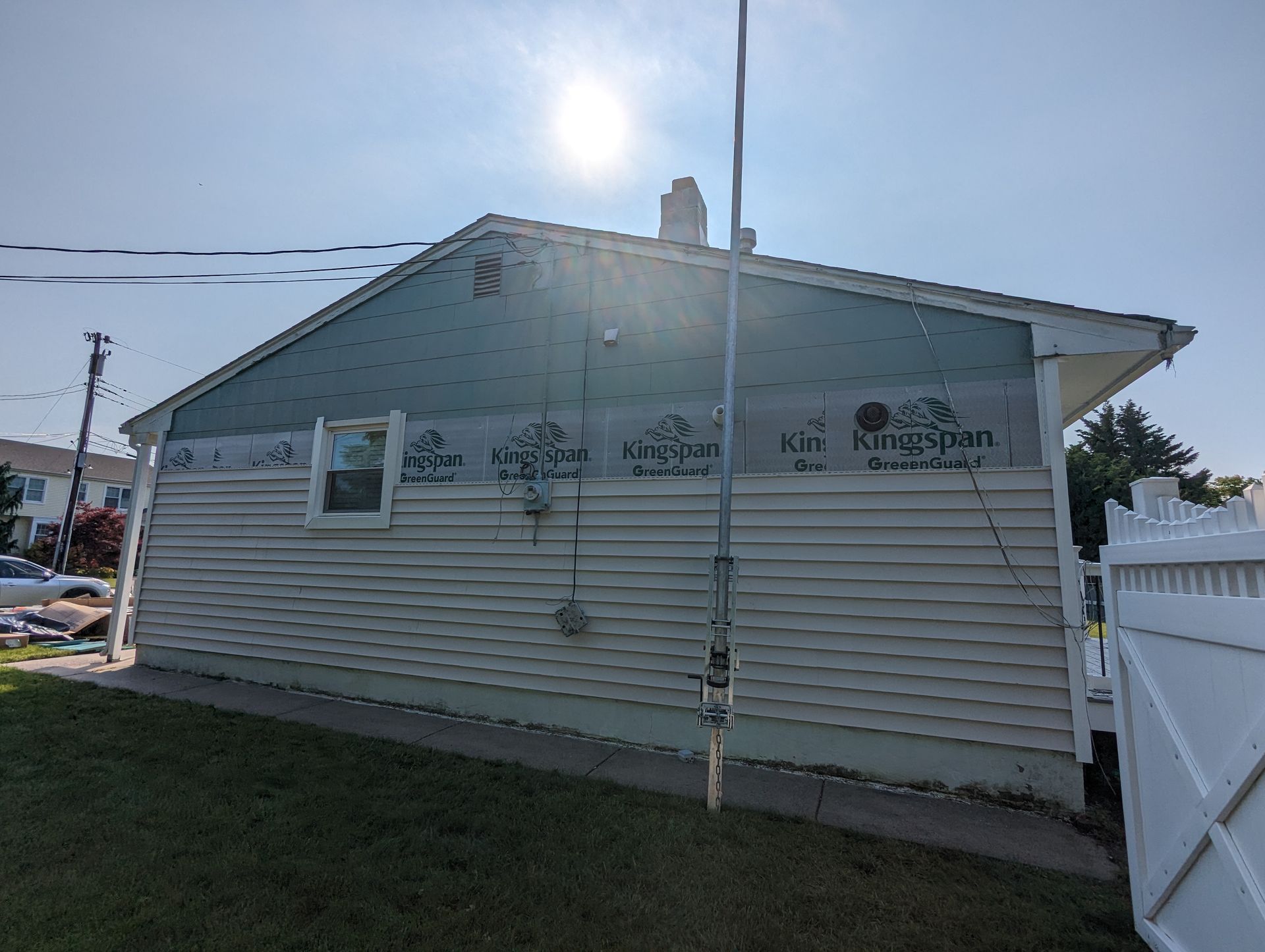A house with a white fence in front of it is being remodeled.