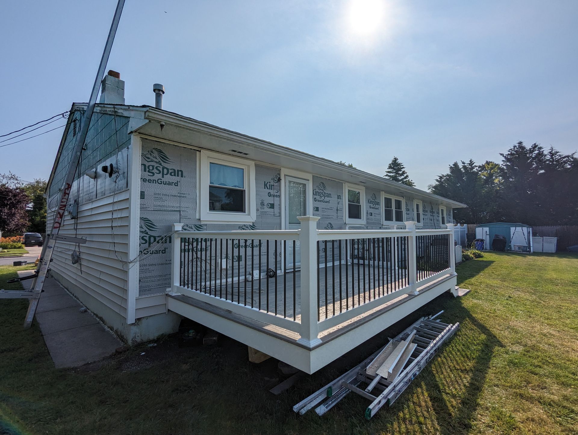 A house with a deck and a ladder in front of it.