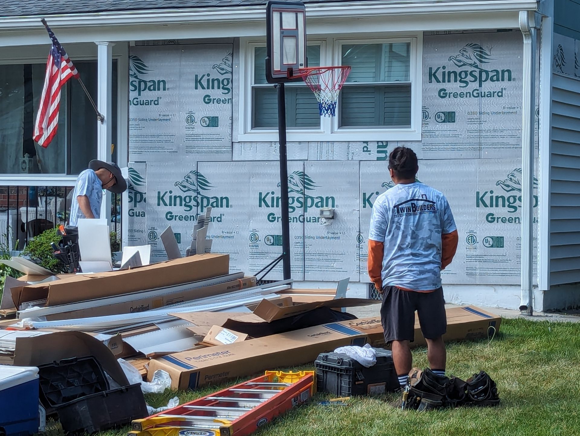 A man is standing in front of a house with a basketball hoop.