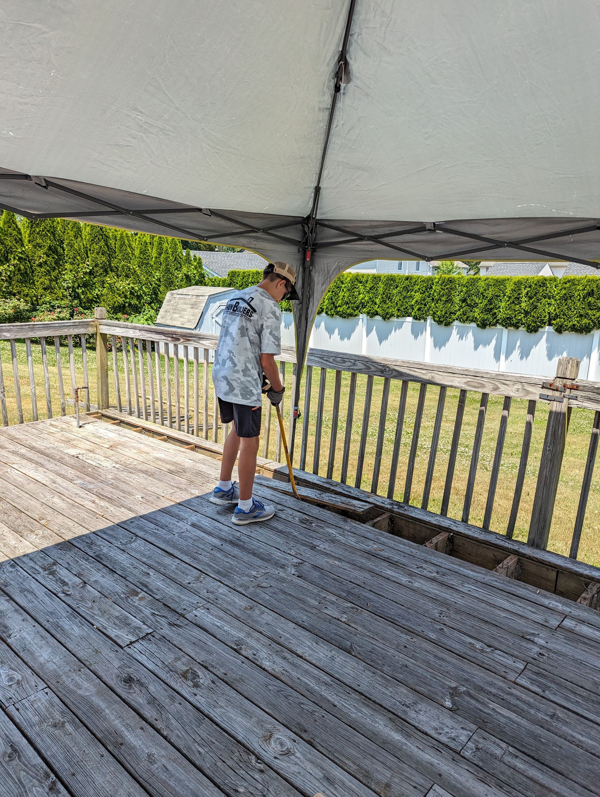A boy is standing on a wooden deck under a tent.