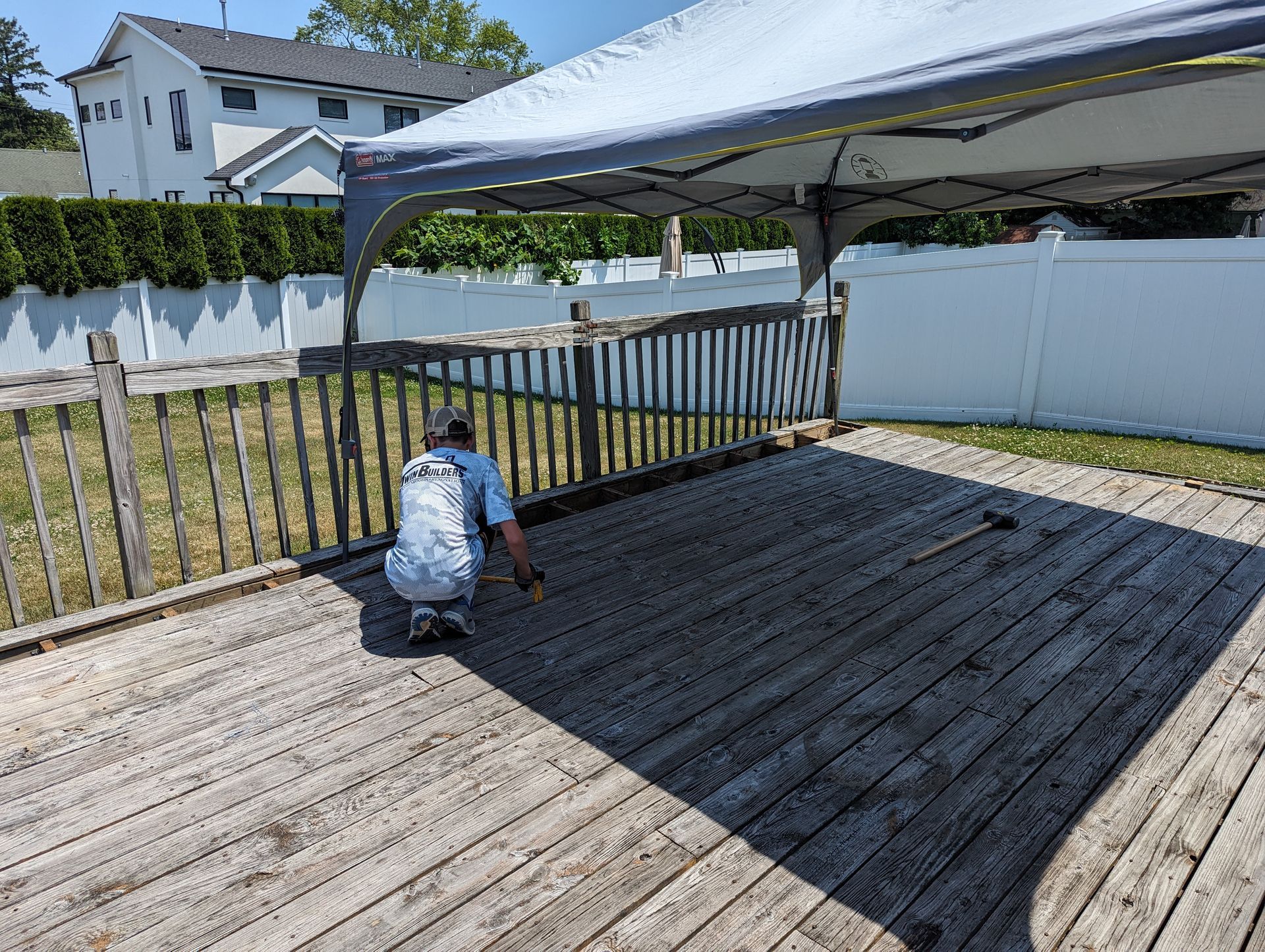 A man is kneeling on a wooden deck under a canopy.