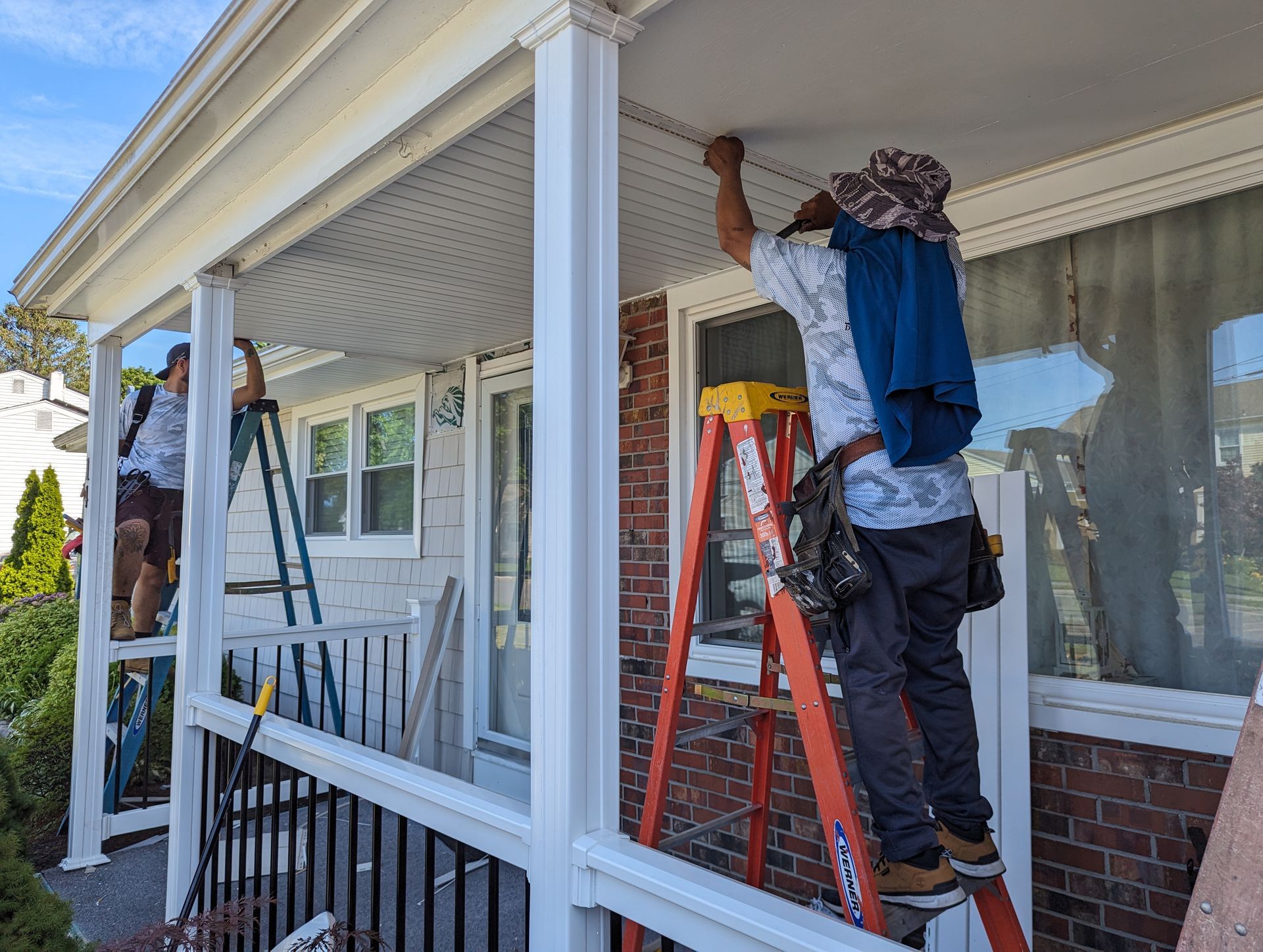 Two men are working on a porch of a house.