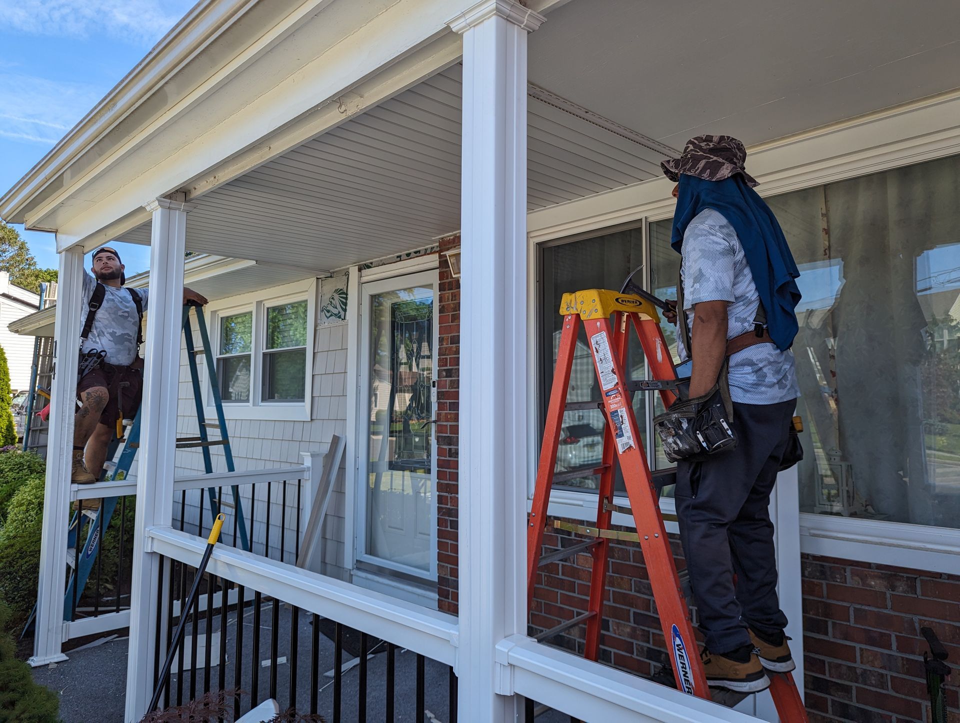 Two men are working on a porch of a house.