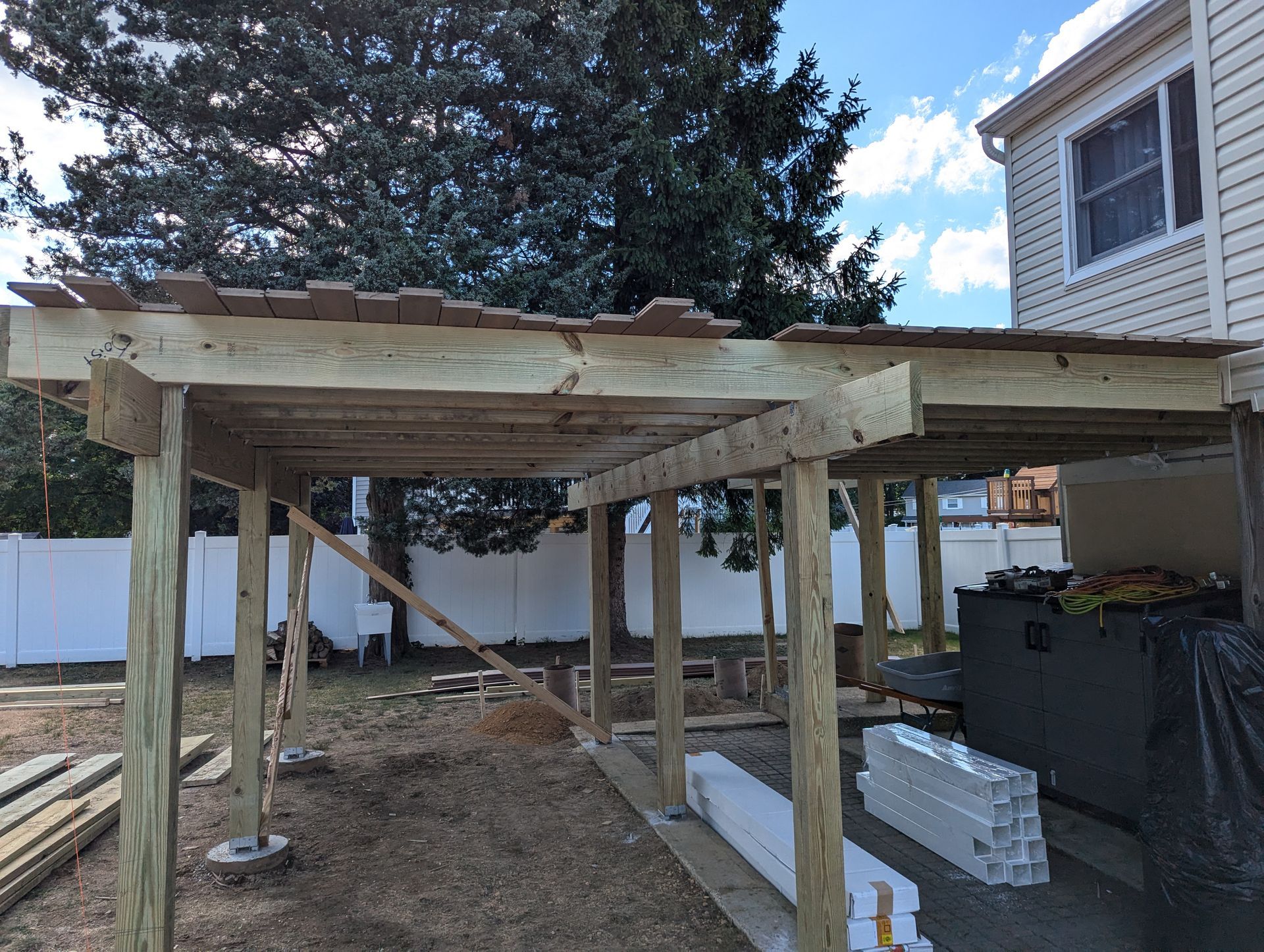 A wooden structure is being built in the backyard of a house.
