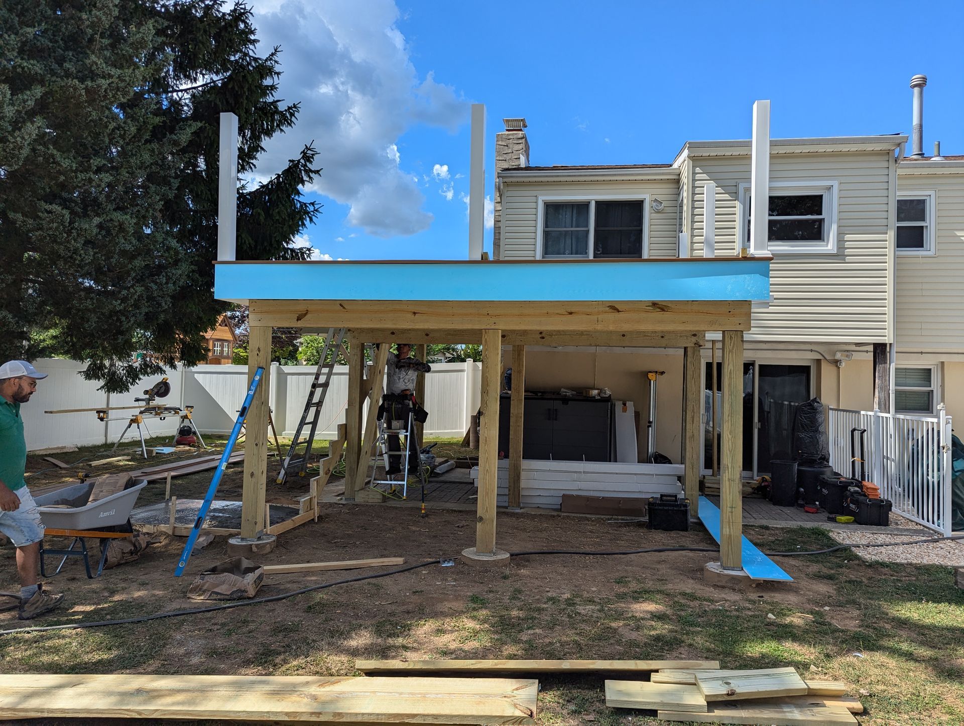 A wooden deck is being built in the backyard of a house