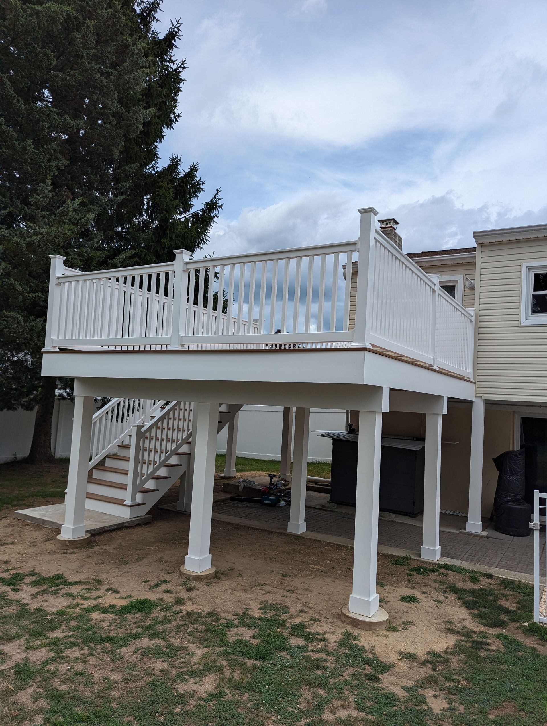 A white deck with stairs is in the backyard of a house.