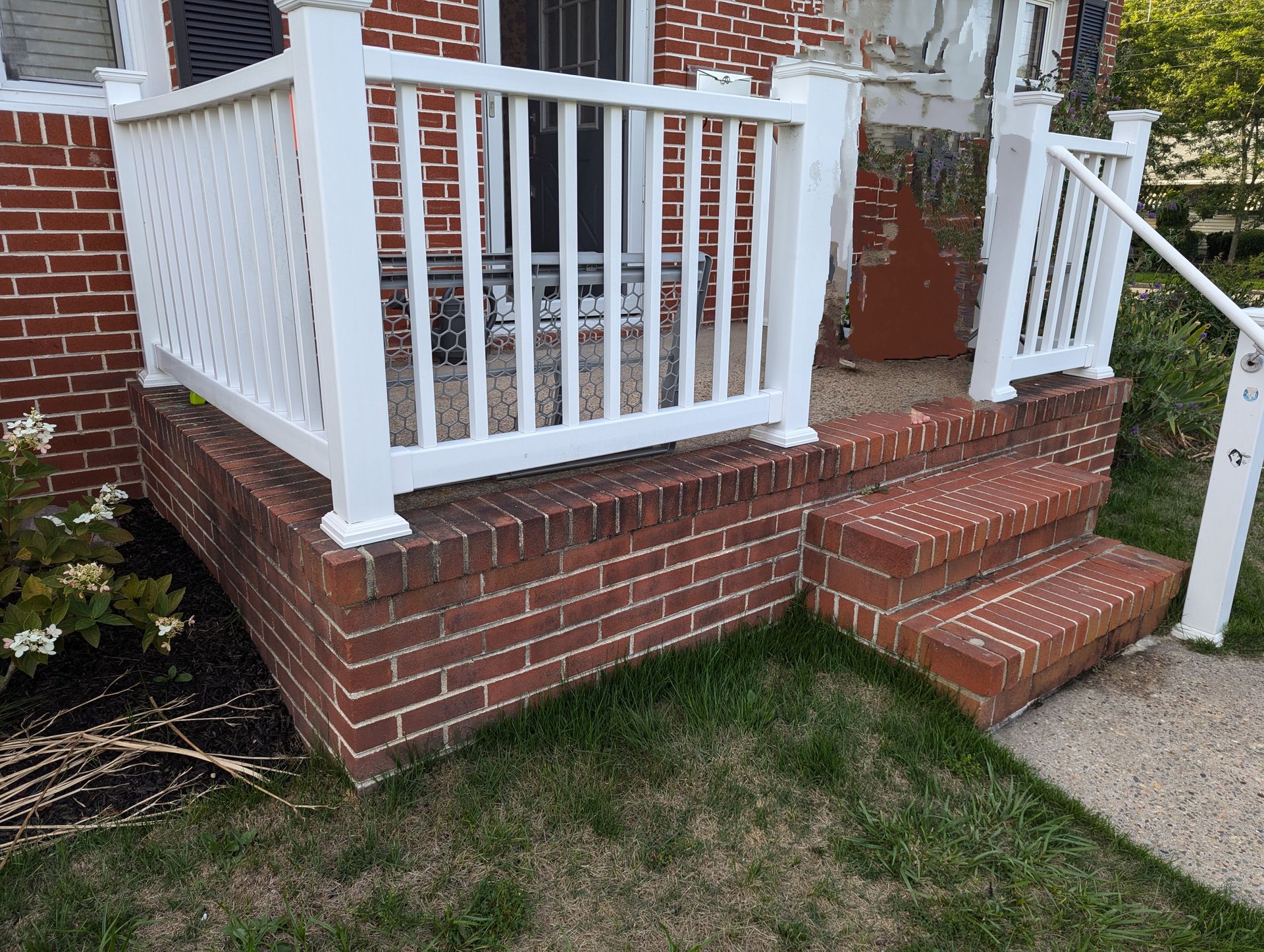 There is a porch with a white railing and stairs.