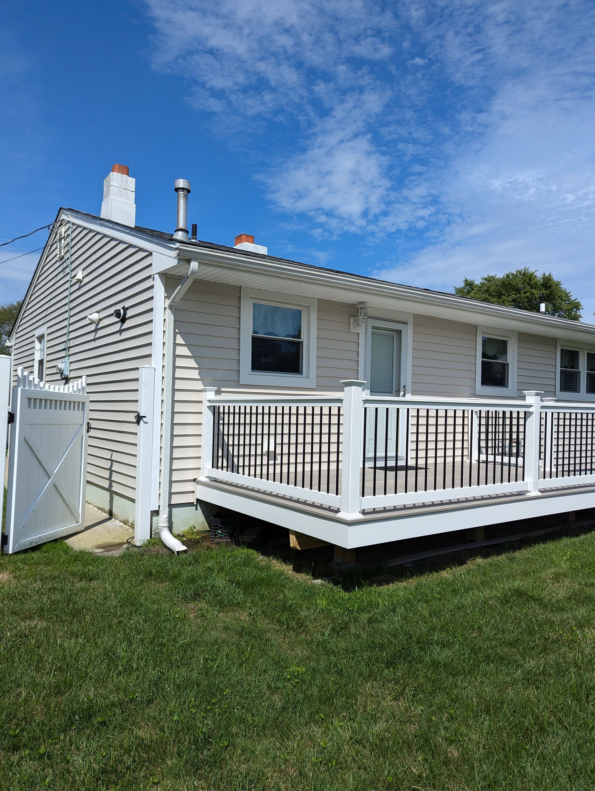 A small house with a deck and fence in the backyard.