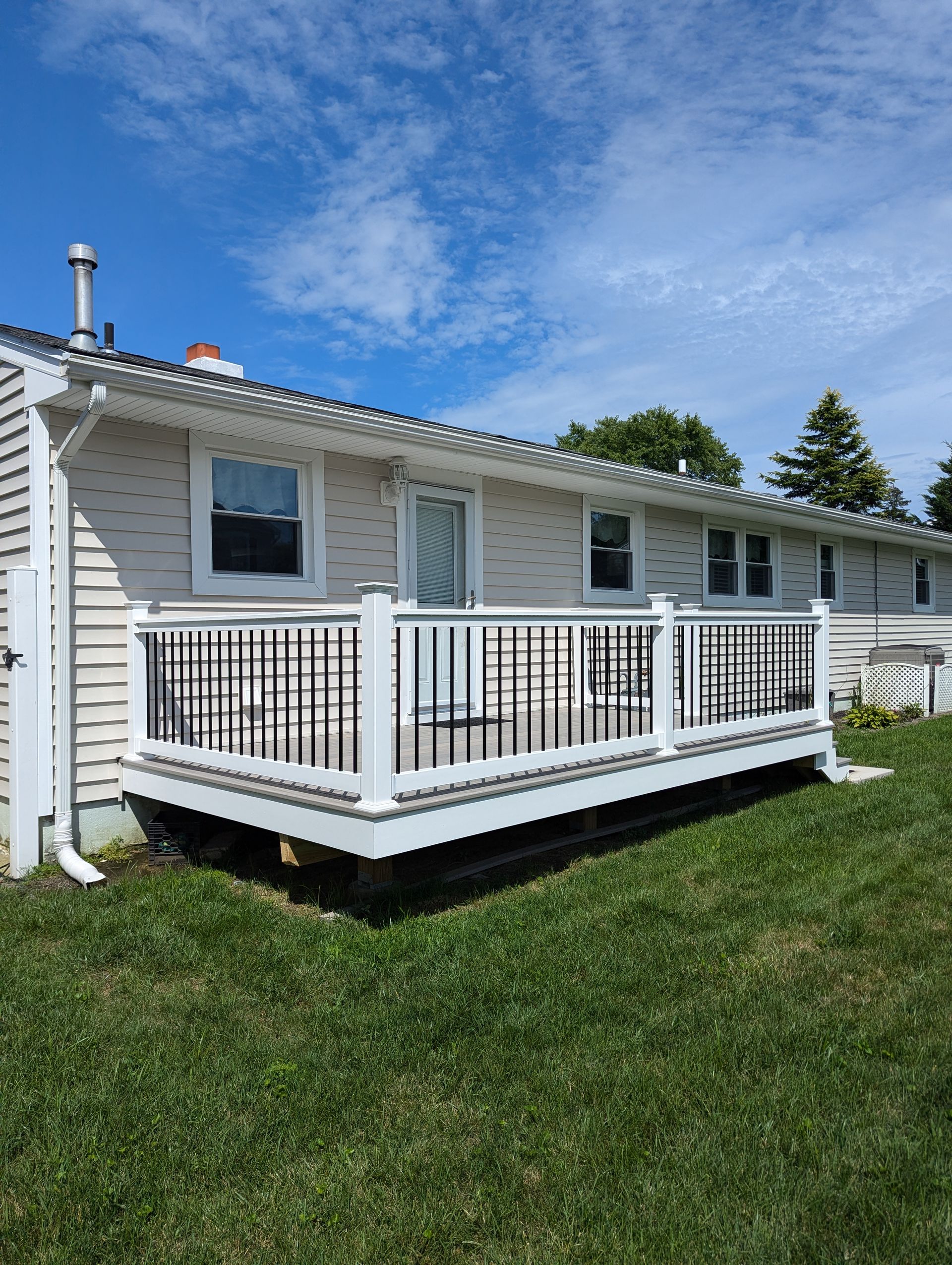 A white house with a large deck in front of it.