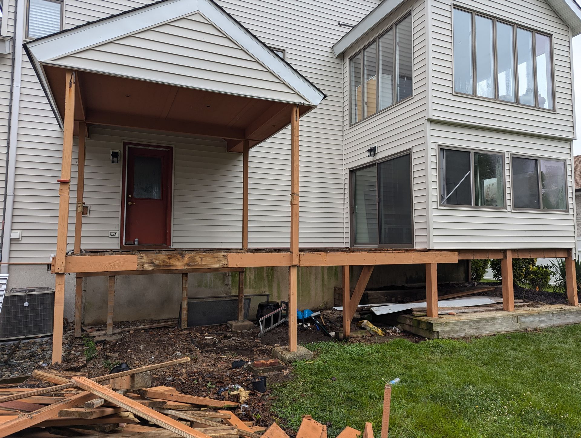 A white house with a wooden deck in front of it.