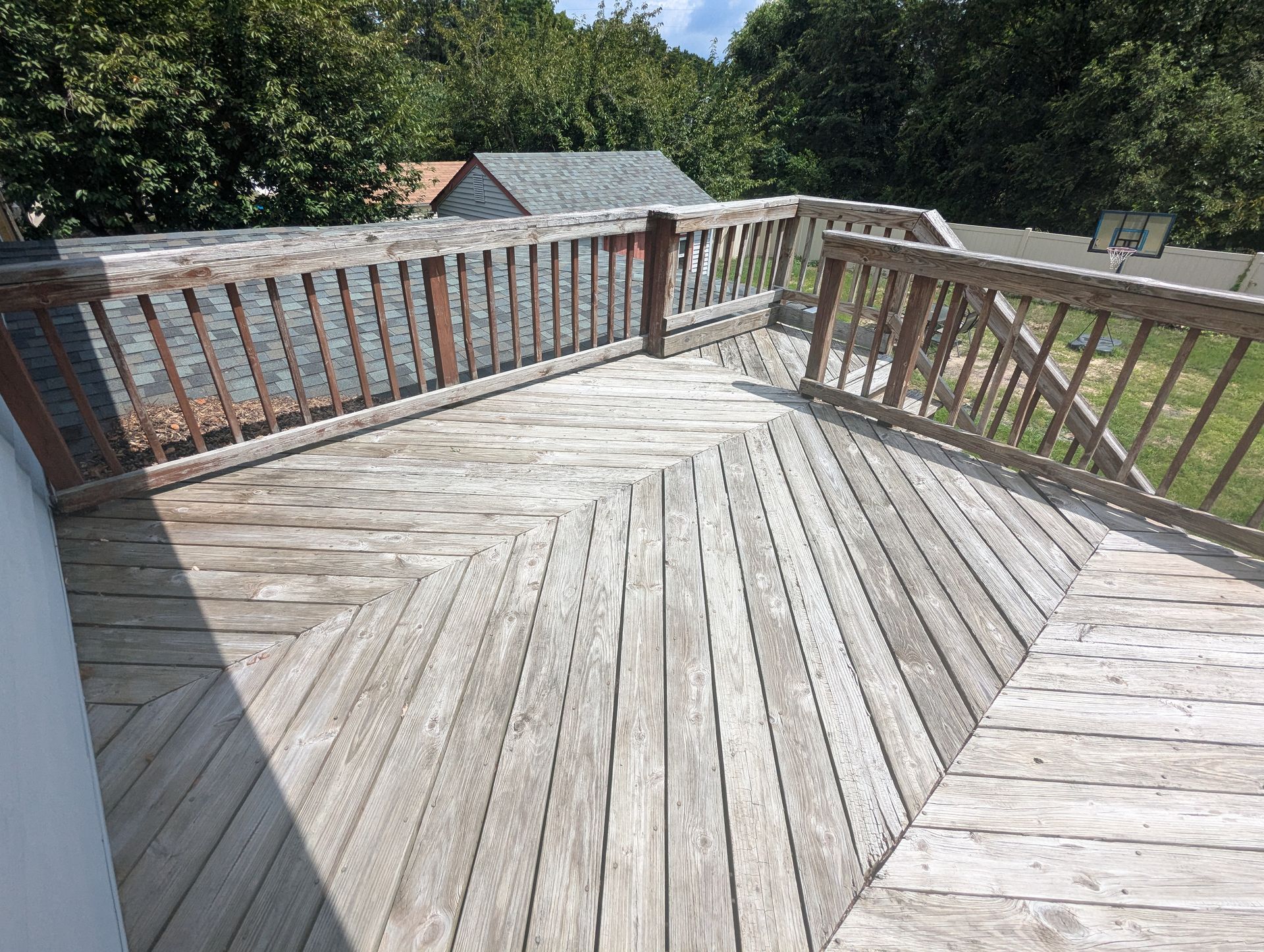 A wooden deck with a wooden railing and trees in the background.