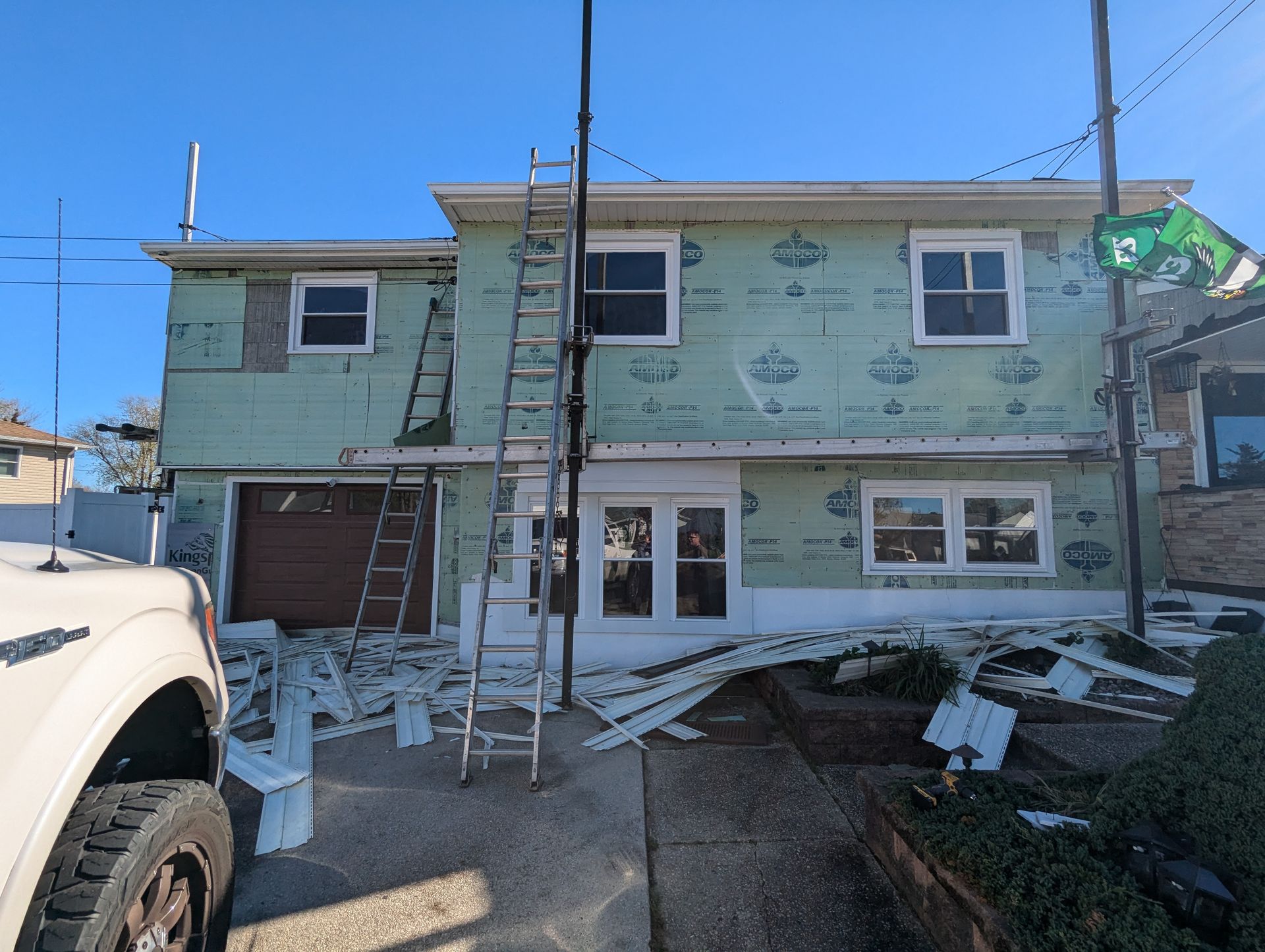 A white truck is parked in front of a house that is being remodeled.