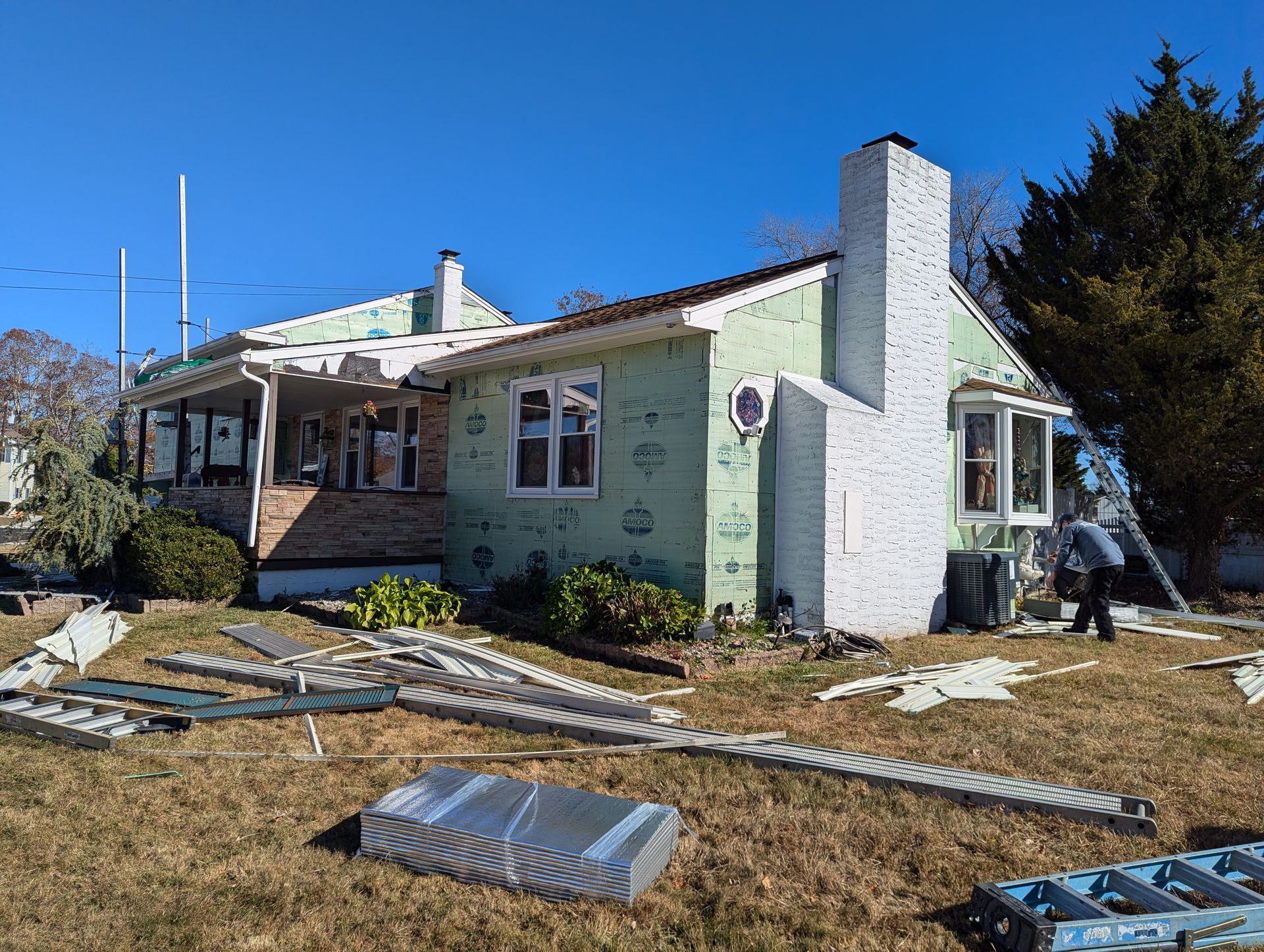 A house is being remodeled with green insulation and a white chimney.