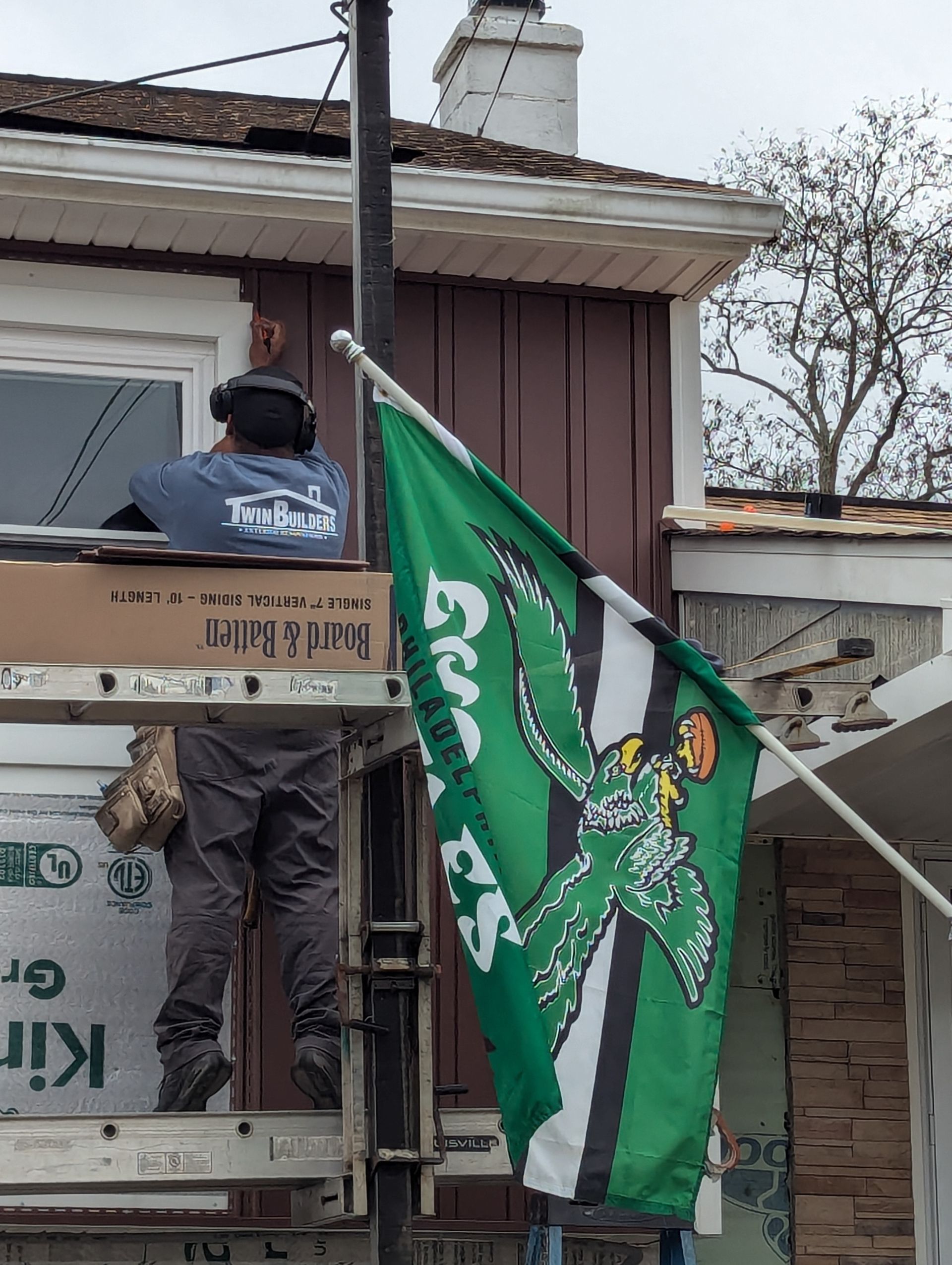 A man is standing on a scaffolding next to a green flag.