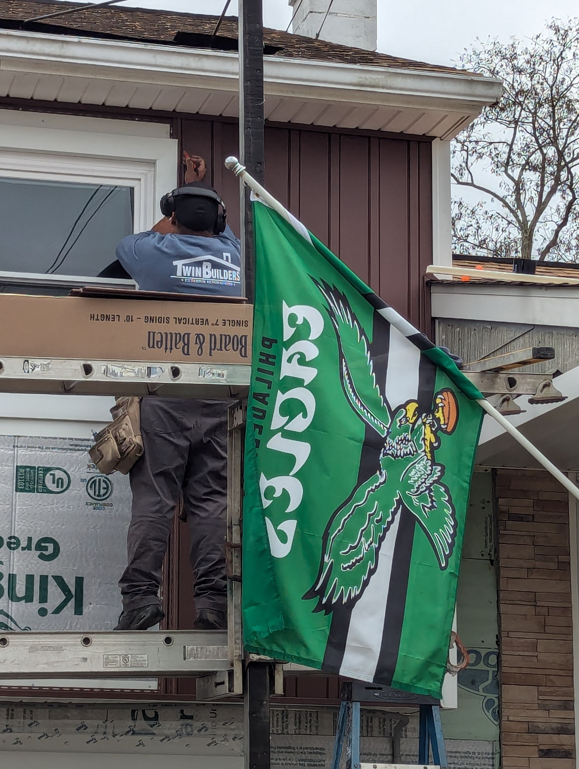 A man is standing on a scaffolding next to a green flag.