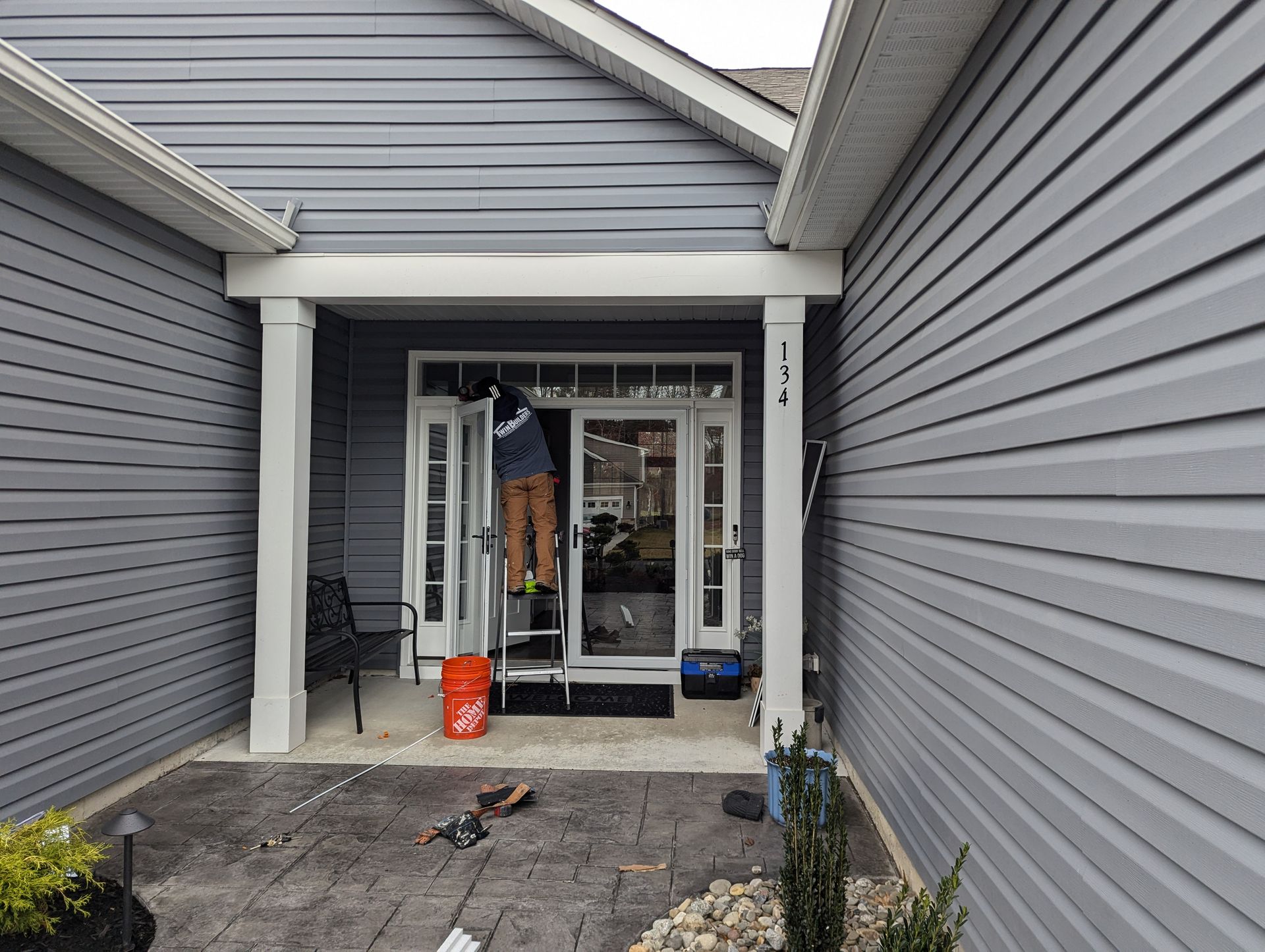 A man is standing on a ladder in front of a house.