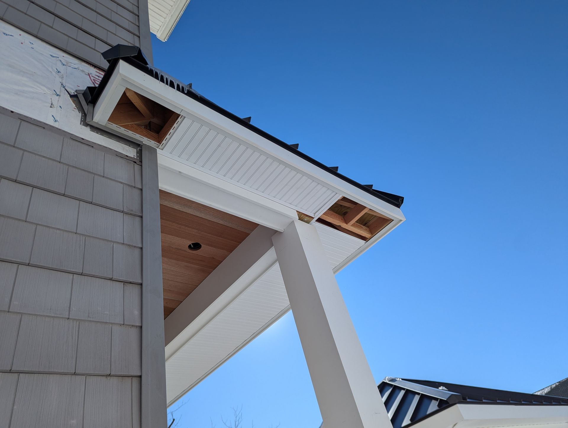 Looking up at the roof of a house with a blue sky in the background