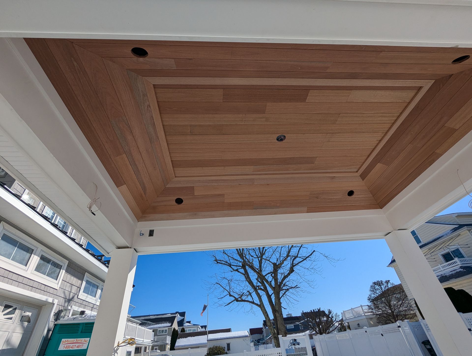 A gazebo with a wooden ceiling and a tree in the background