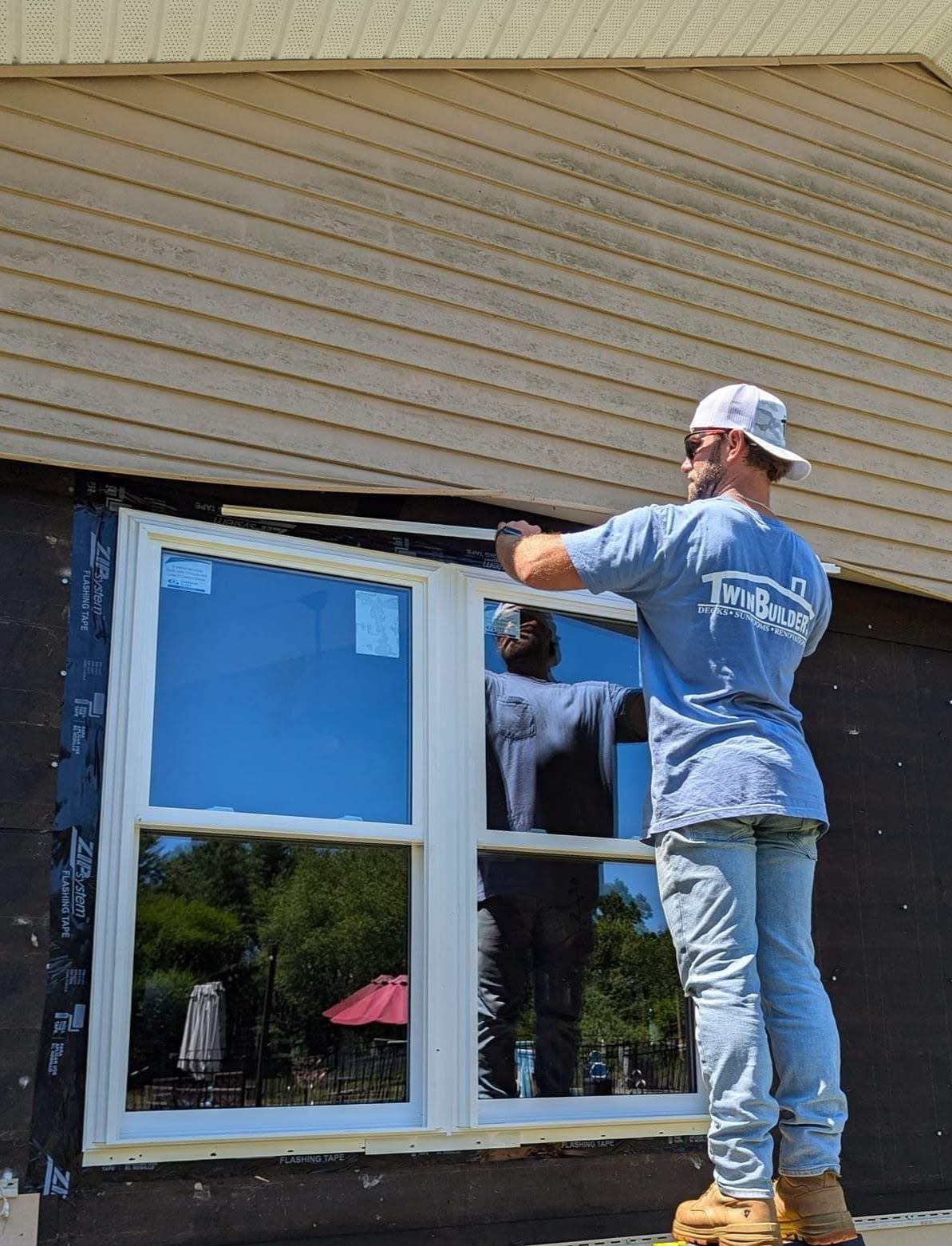 A man is installing a window on the side of a house.