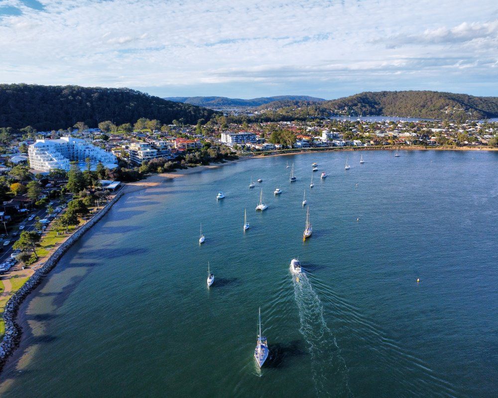 Boats Sail On A Blue Bay, With A Town — NLJ Partners P/L In Wyong, NSW