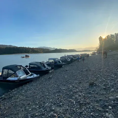 A row of boats are parked on the shore of a river.