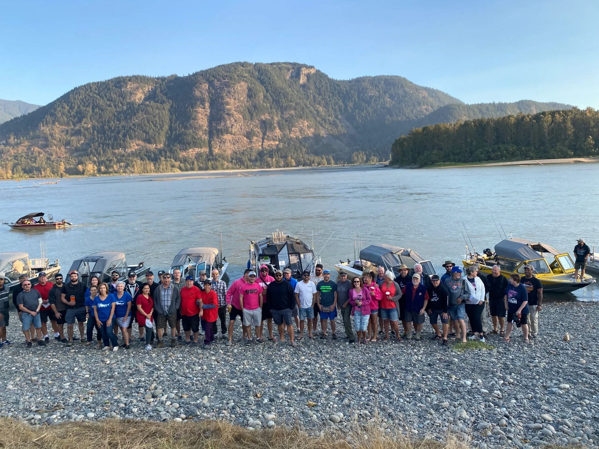 A large group of people are standing on the shore of a lake.