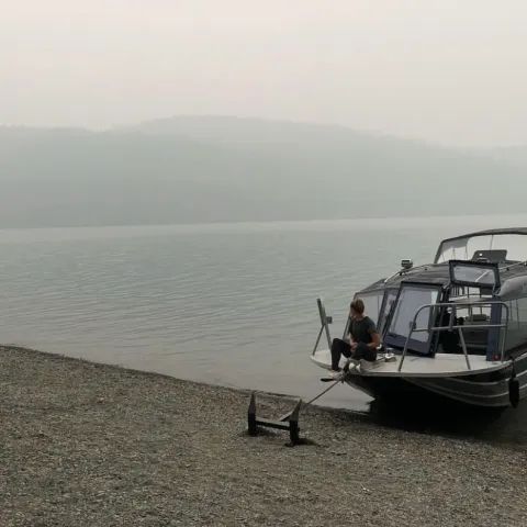 A boat is docked on the shore of a lake.