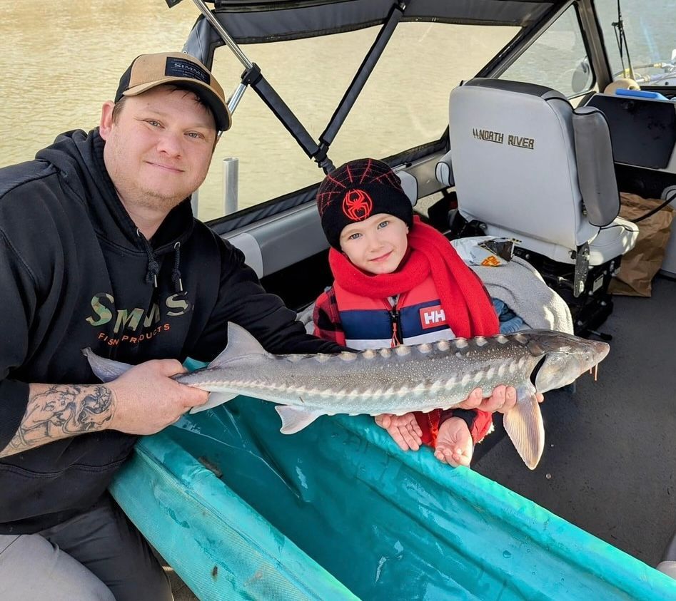 A man and a child are holding a large fish in a boat.