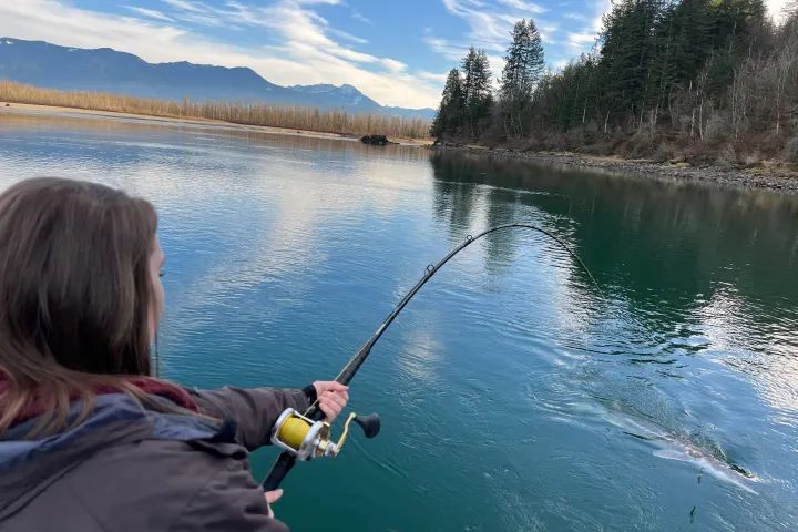 A woman is fishing in a lake with a fishing rod.
