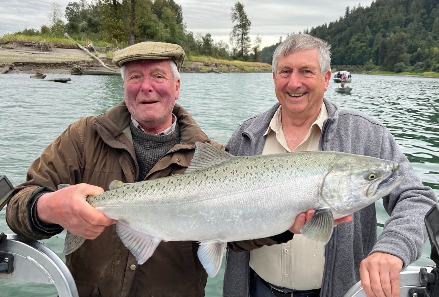 Two men are standing next to each other holding a large fish.