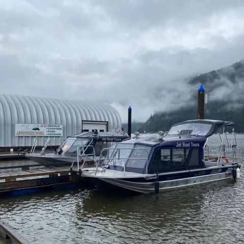 Two boats are docked in a marina next to a building.
