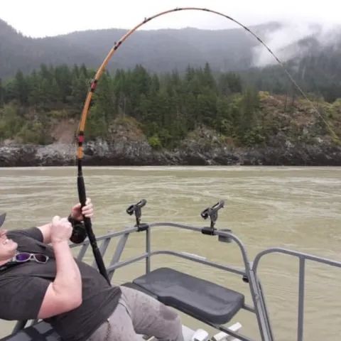 A man is fishing on a boat in the water.