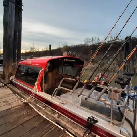 A red and silver boat with fishing rods attached to it
