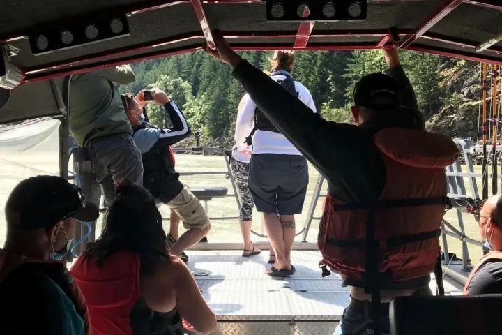 A group of people are standing on a boat looking out the window.