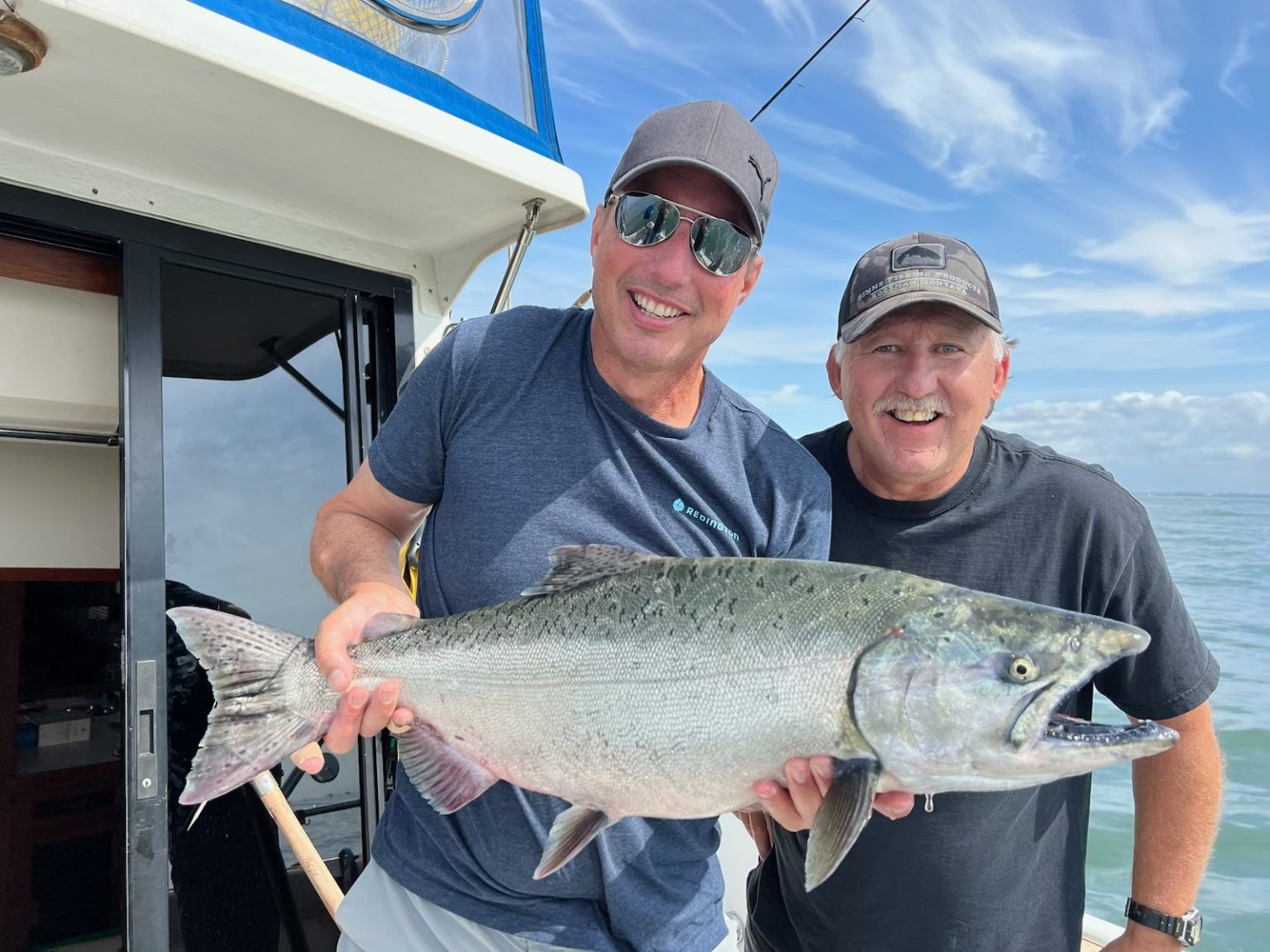 Two men are holding a large fish on a boat.