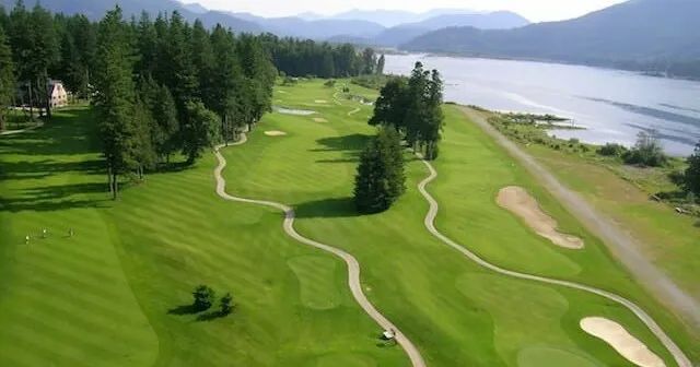 An aerial view of a golf course with a lake in the background