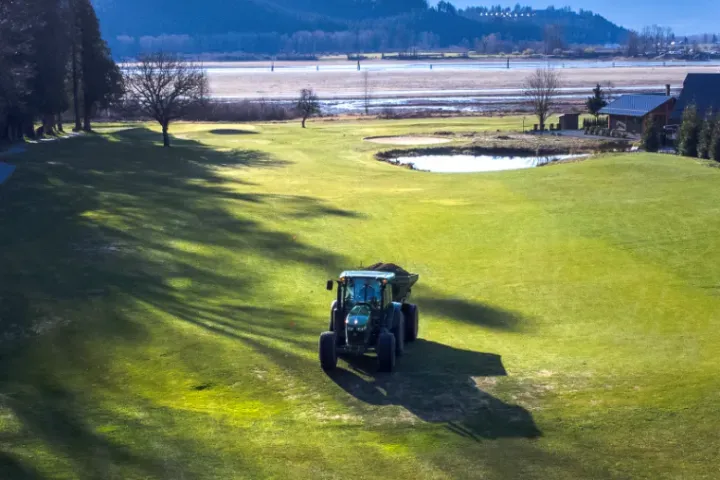An aerial view of a tractor plowing a golf course.