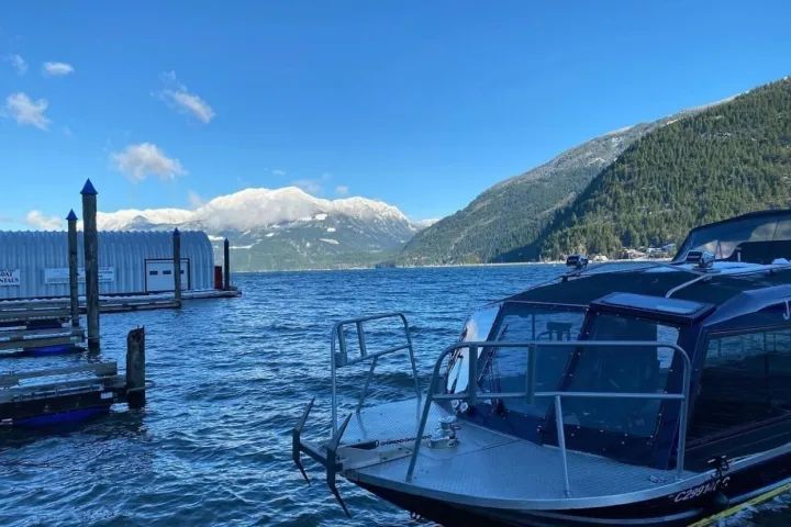 A boat is docked at a dock on a lake with mountains in the background.