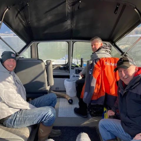 A group of men are sitting in the back of a boat.