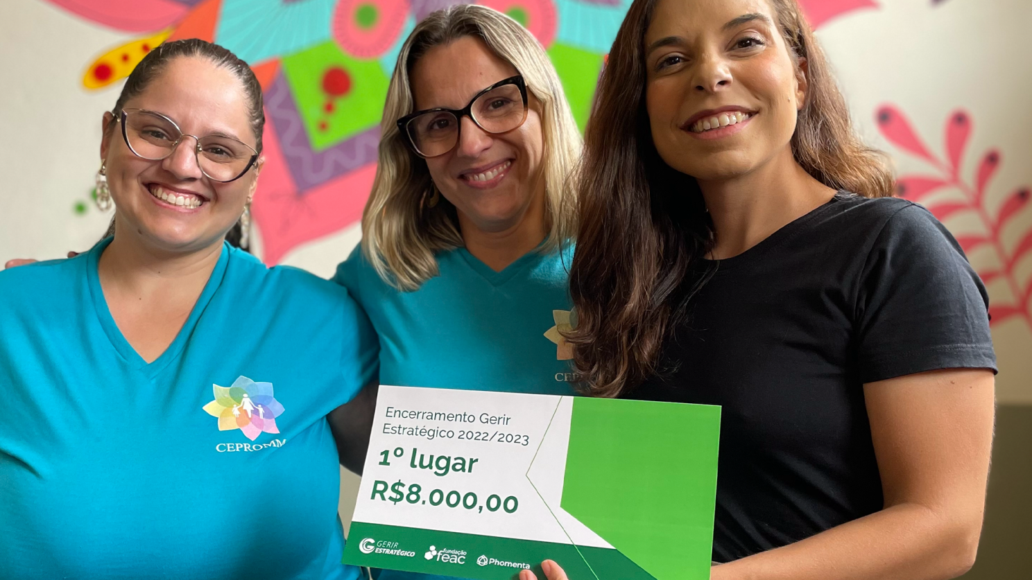 Três pessoas sorridentes seguram um certificado verde de 