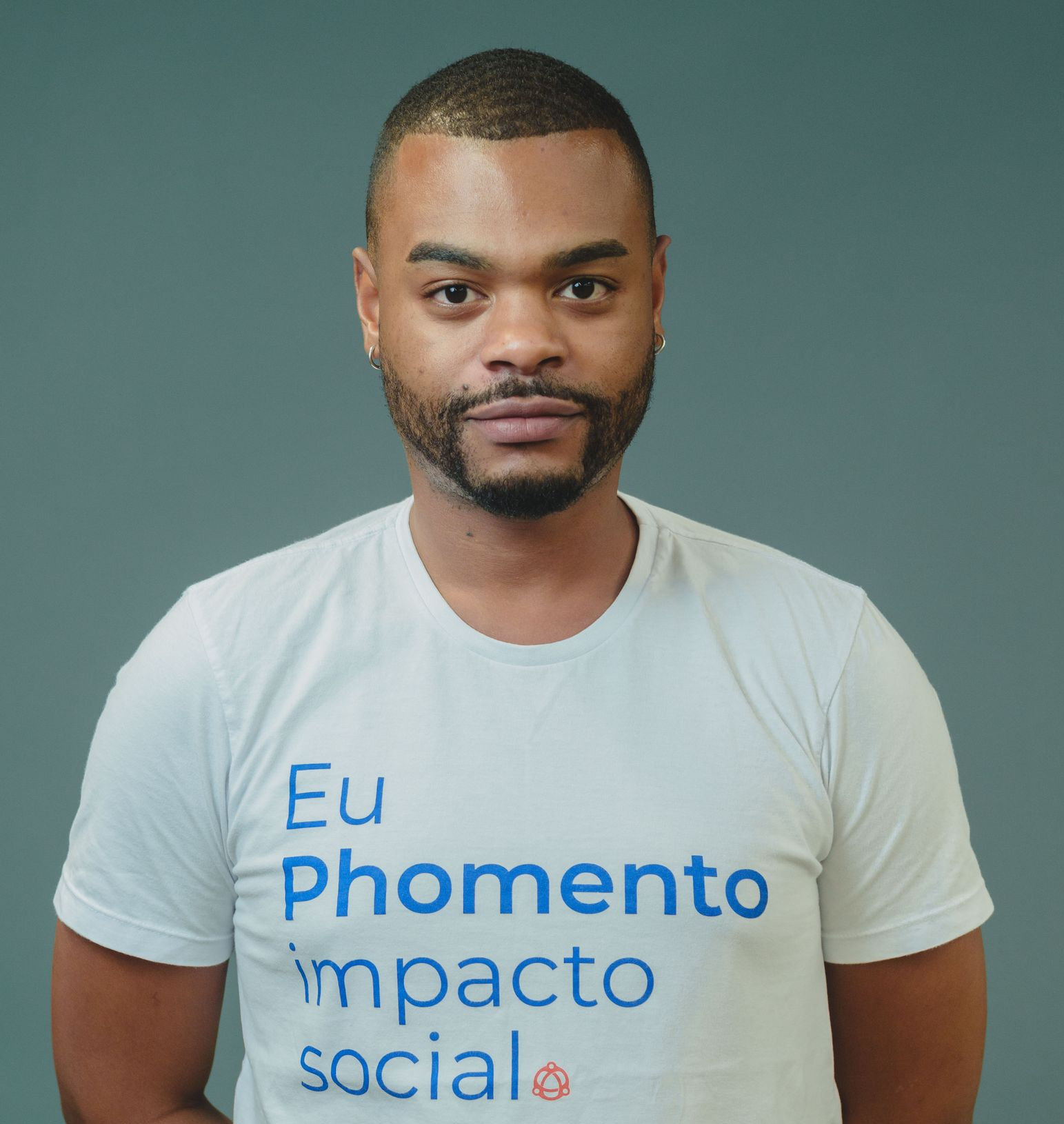 Pessoa vestindo camiseta branca com estampa azul em pé contra um fundo verde liso.