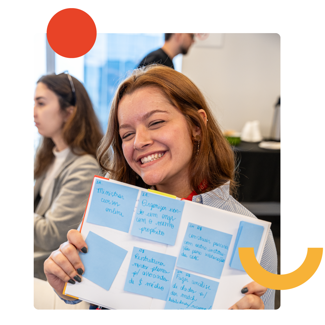 Mulher sorridente segurando folha de papel com anotações.