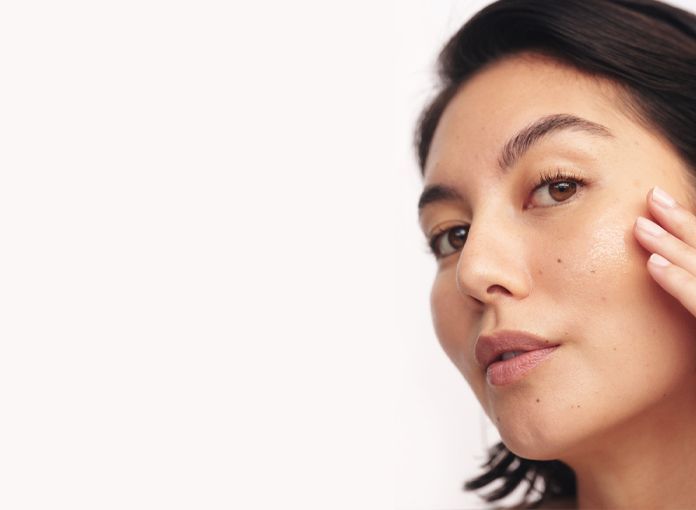 Woman touching cheek, looking at the camera with clear skin, against a white background — Aqua Marine Skin and Beauty in Tuncurry, NSW
