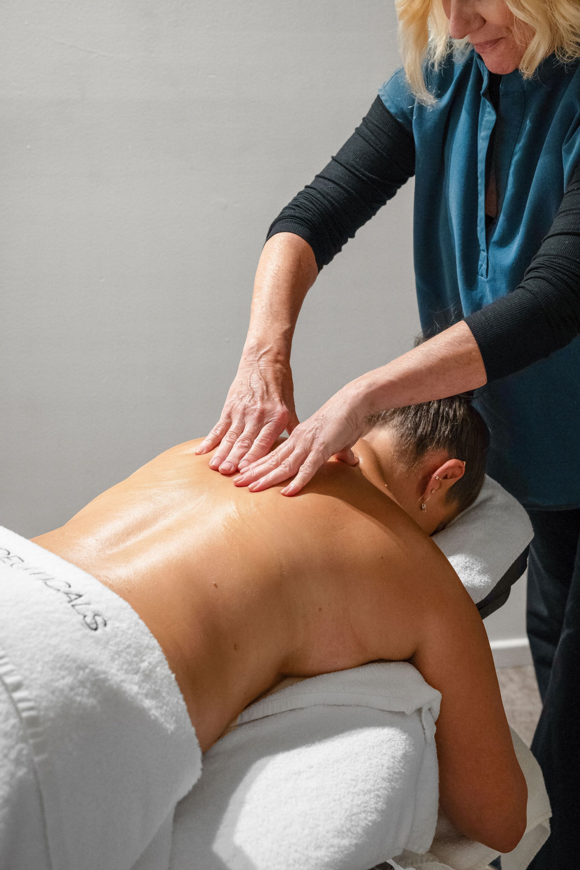 Person receiving a back massage at a spa. Therapist's hands are on the client's oiled back  — Aqua Marine Skin and Beauty in Tuncurry, NSW