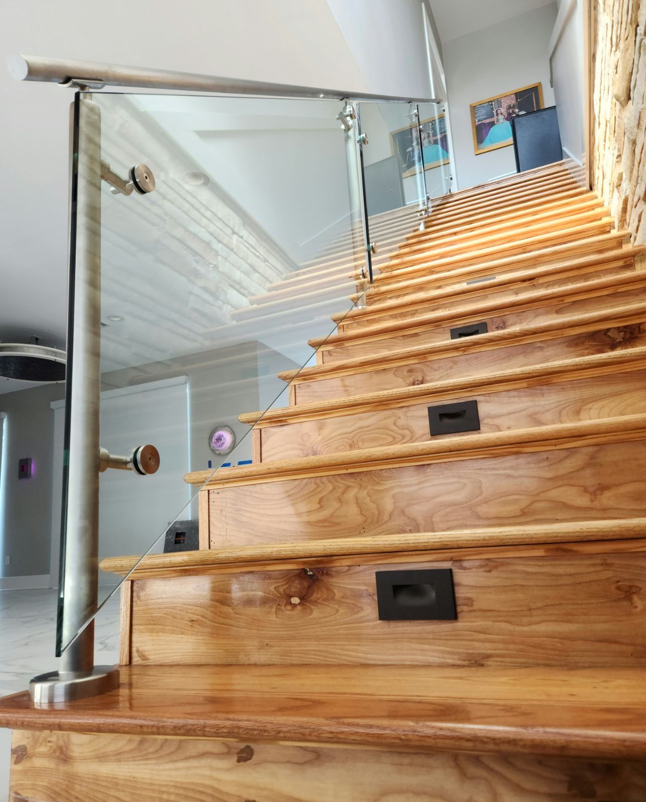 A wooden staircase with a glass railing in a house.