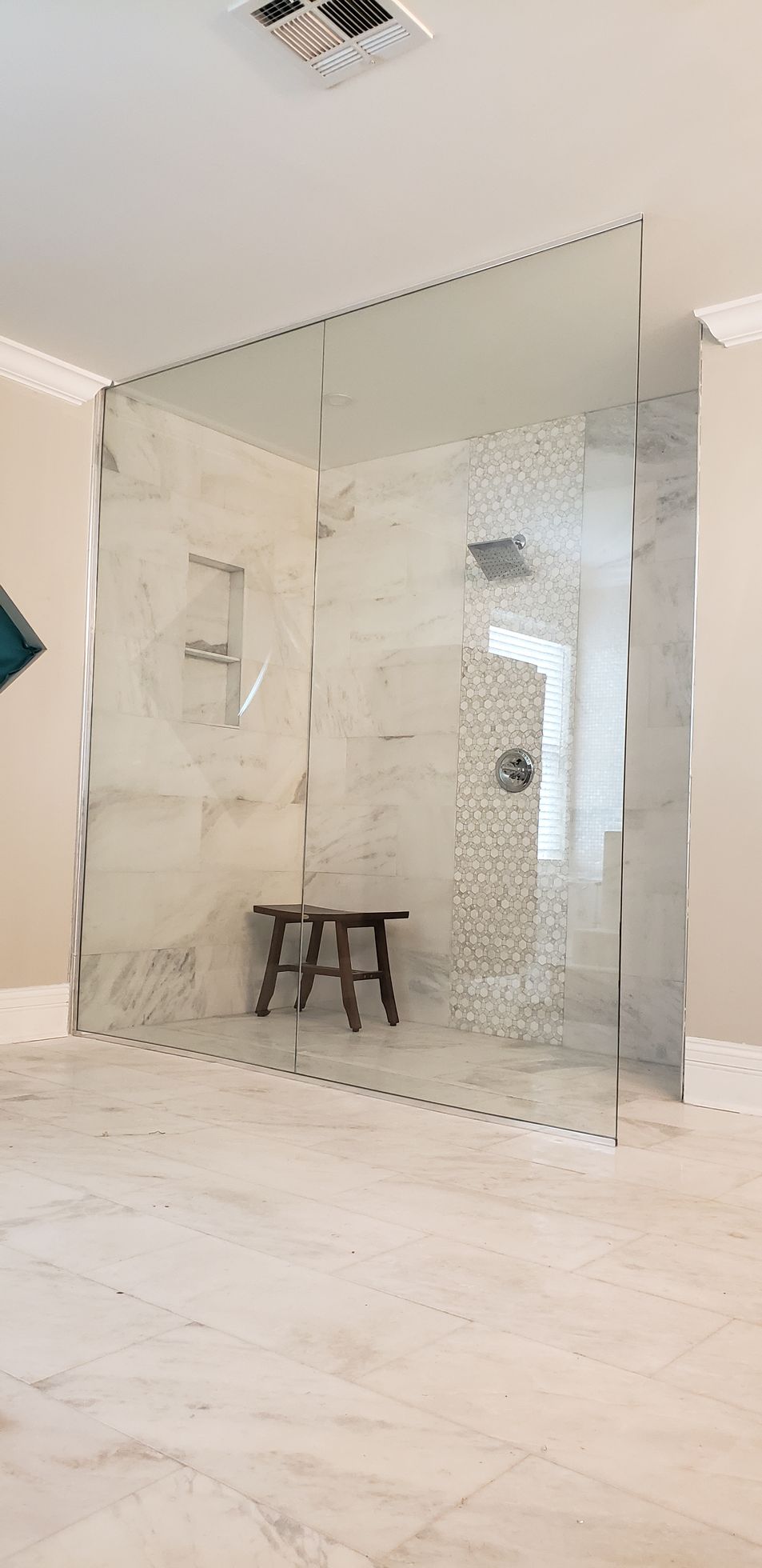 A bathroom with a walk in shower and a bench.