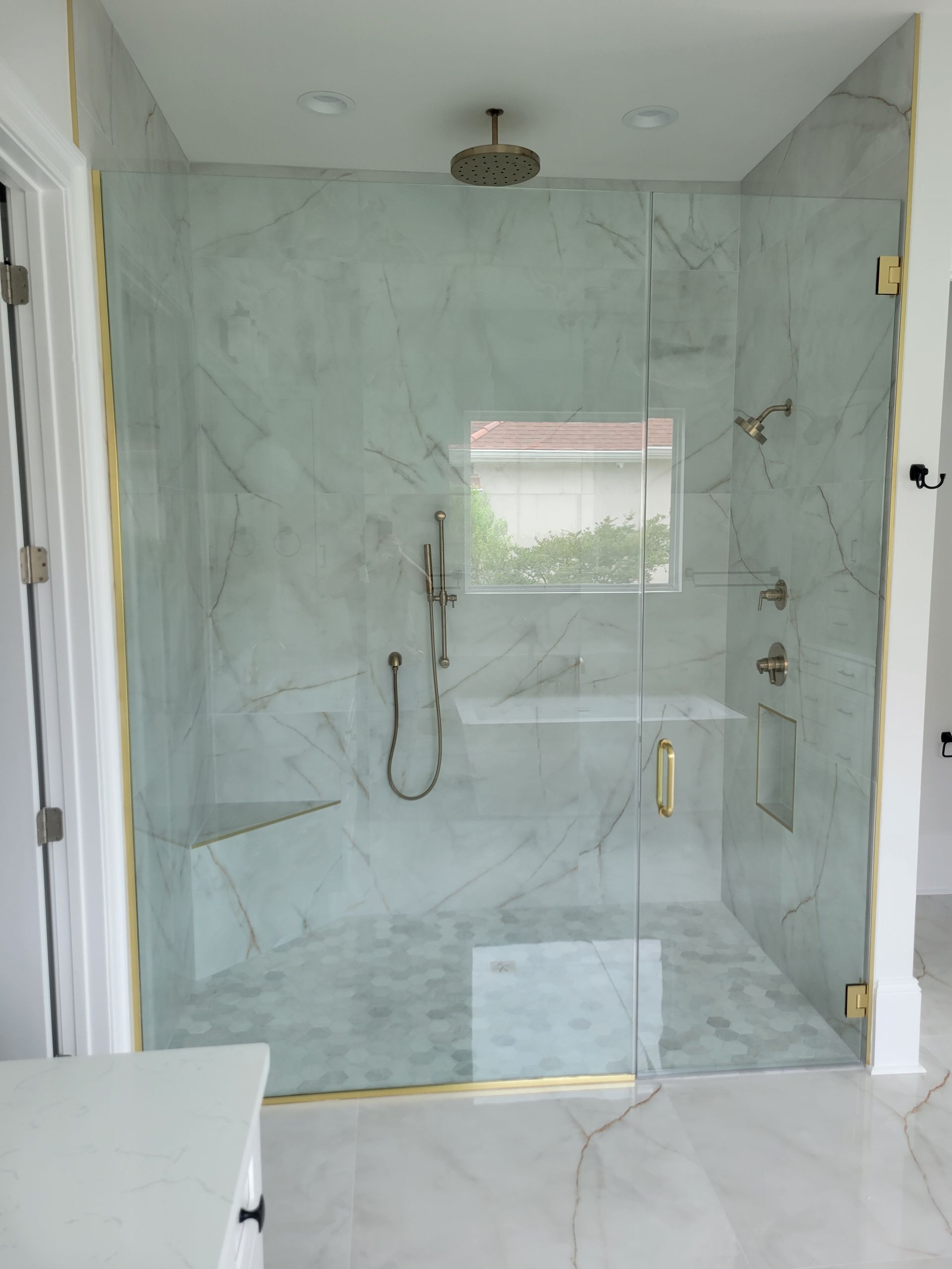 A bathroom with a walk in shower with a glass door
