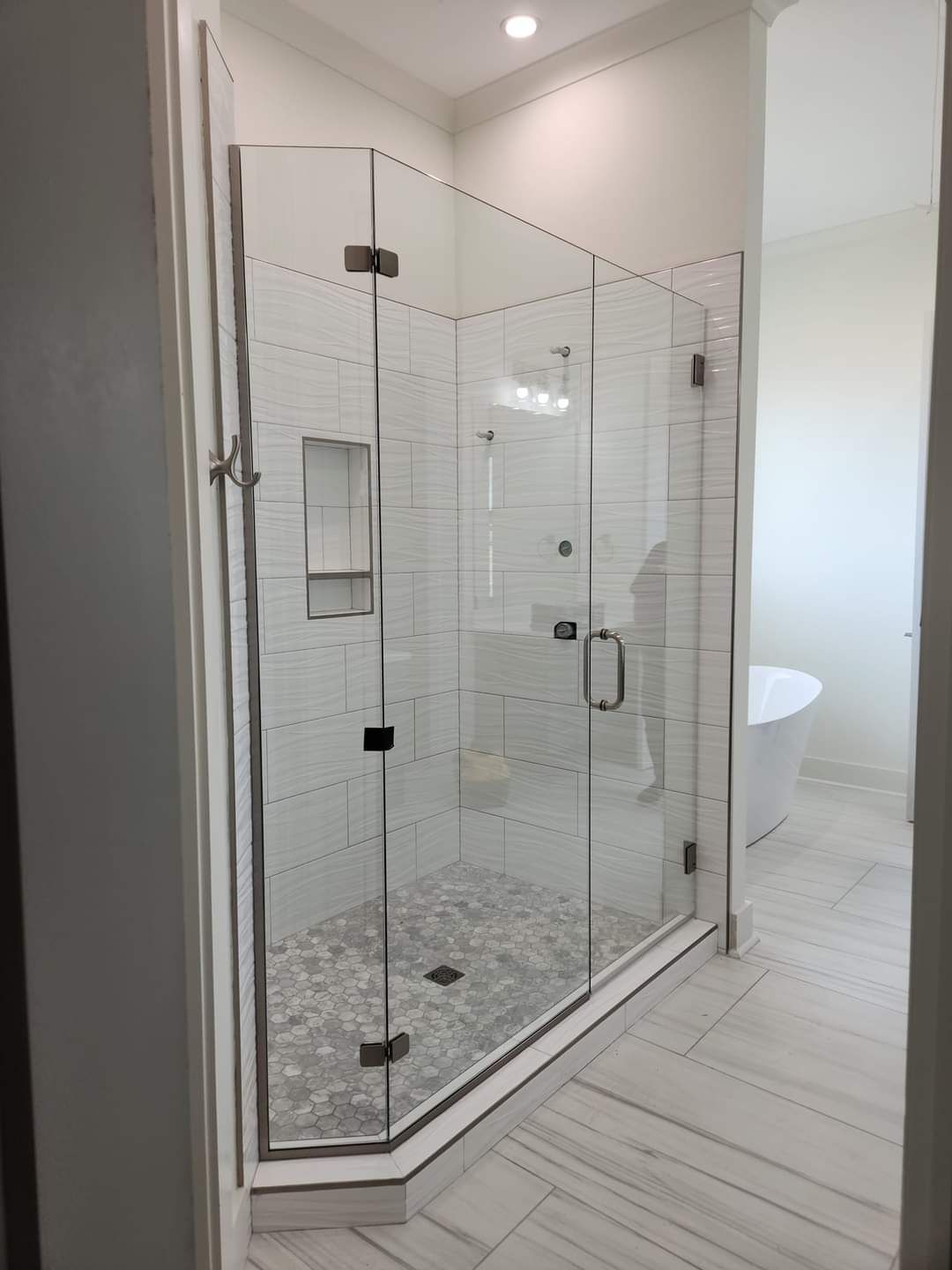 A bathroom with a walk in shower with a glass door.